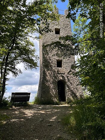 Wallerwarte (Ebermannstadt, Fränkische Schweiz) Steinerner Turm im Wald mit Bank im Vordergrund, blauer Himmel im Hintergrund.