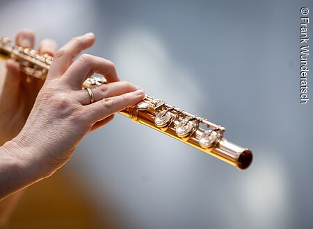 Zwei schlanke Hände halten eine Querflöte